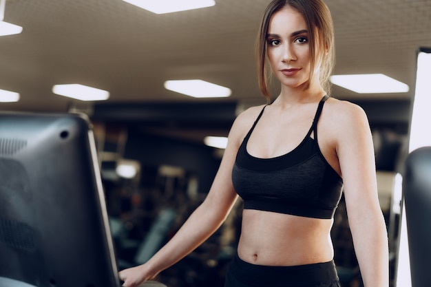 Pretty fit woman in black sportrswear training on a treadmill