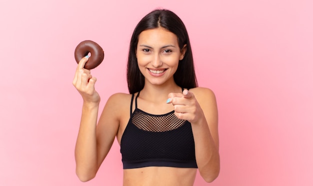 Bella donna fitness con una ciambella e una ciotola per la colazione