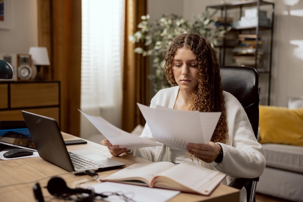 Pretty focused girl student looking at many documents schedules reports preparing for the exam