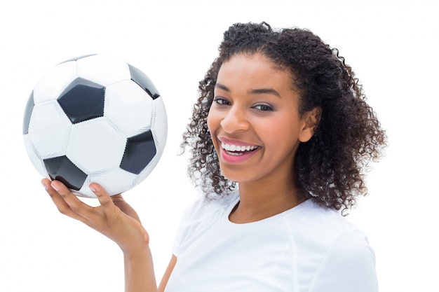 Pretty football fan in white holding ball smiling at camera