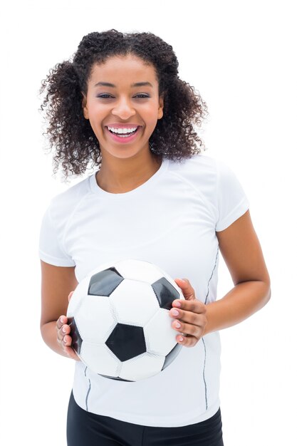 Pretty football fan in white holding ball smiling at camera