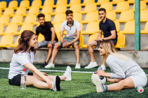 Uomo grazioso del giocatore di football che allunga il muscolo della gamba che si prepara per la partita nello stadio