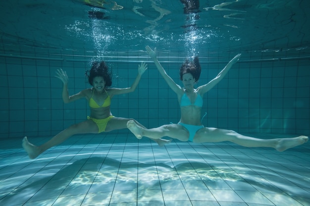 Pretty friends smiling and posing for camera underwater