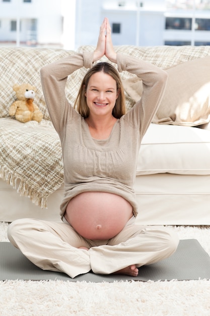 Pretty future mother doing yoga position on the floor