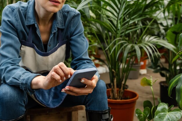 Foto grazioso lavoratore del centro di giardinaggio che parla al telefono con il cliente