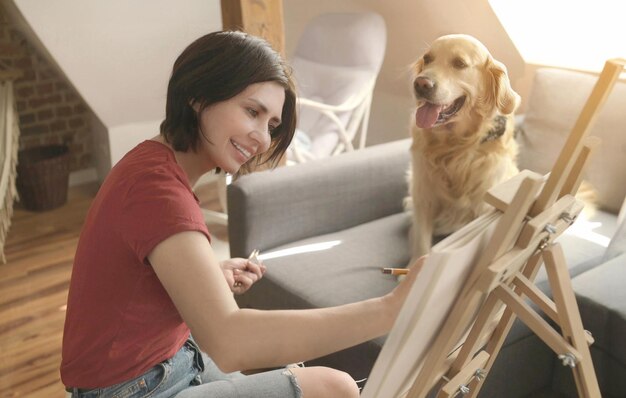 Pretty girl artist drawing sketch with golden retriever dog using pencil and canvas beautiful young