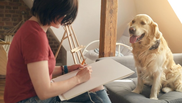 Foto bella ragazza artista disegno schizzo con cane golden retriever