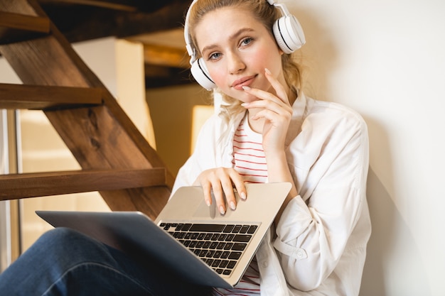 Pretty girl. Attractive female keeping smile on her face, holding laptop on her knees