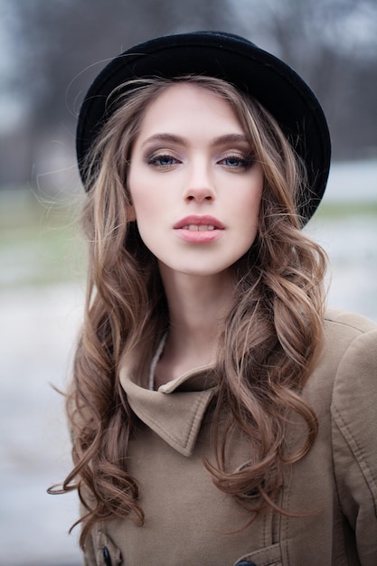 Pretty girl in black hat outdoors portrait