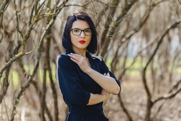 Pretty girl in black suit among bushes