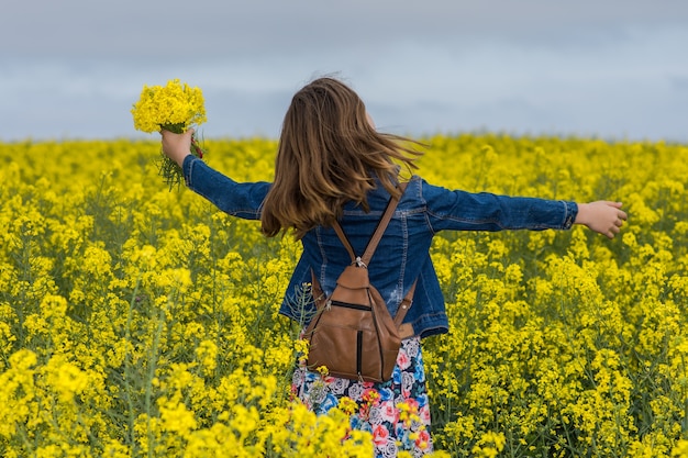 Pretty girl in blooming yellow field with rape