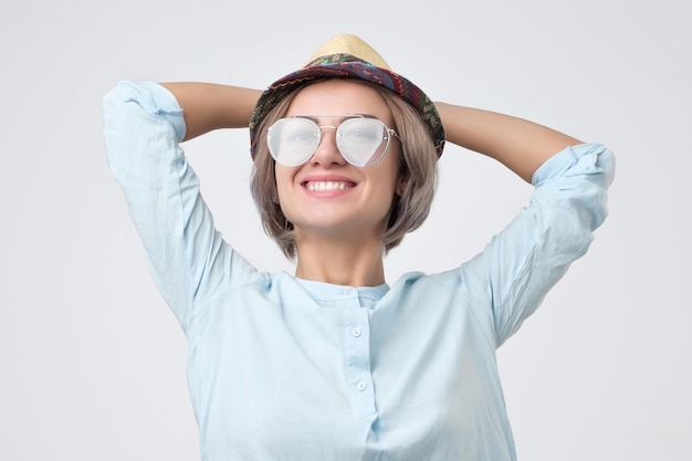 Pretty girl in blue shirt hat and sunglasses posing with smile