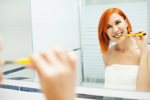 Pretty girl brushes her teeth in a bright bathroom