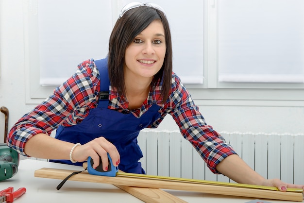 Pretty girl builder measuring a plank of wood