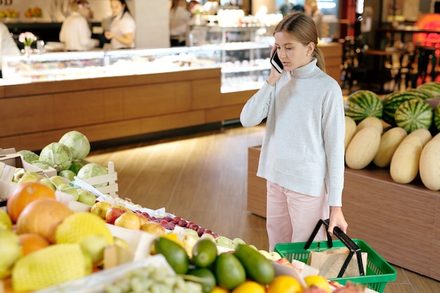 Pretty girl in casualwear talking to her mom on mobile phone