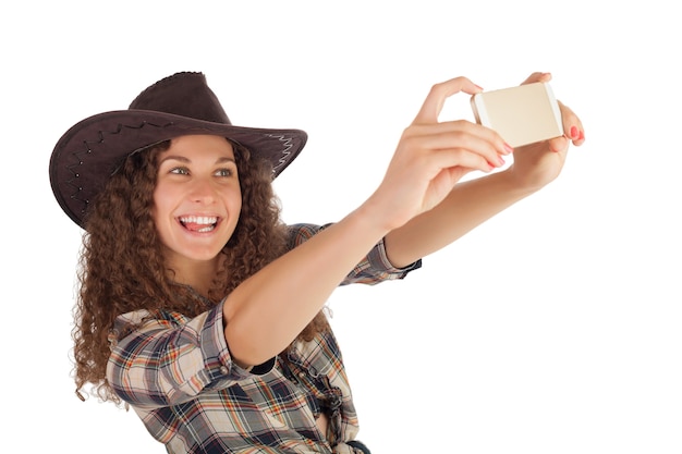 Pretty girl in cowboy style making selfie on her smartphone.