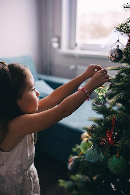 Pretty girl decorating christmas tree with balls