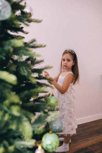 Pretty girl decorating christmas tree with baubles