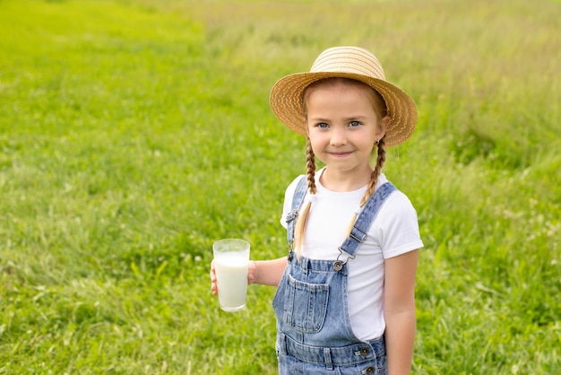 かわいい女の子がグラスからヤギのミルクを飲みます。農産物のコンセプト、天然山羊乳