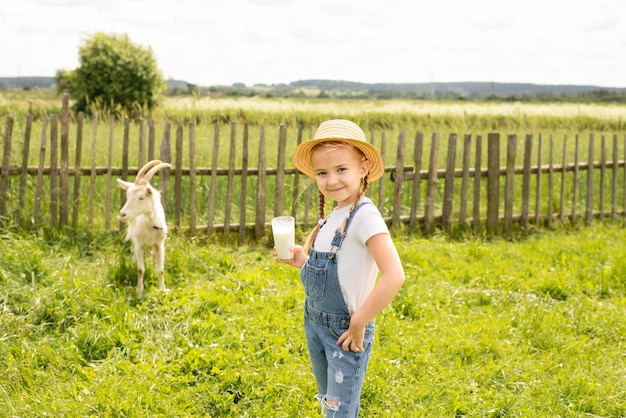 Una bella ragazza beve il latte di capra da un bicchiere. il concetto di prodotti agricoli, latte di capra naturale