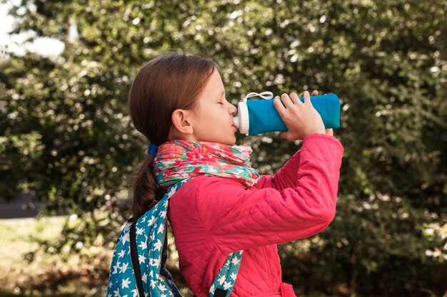 Foto bella ragazza beve acqua da una bottiglia di silicone riutilizzabile