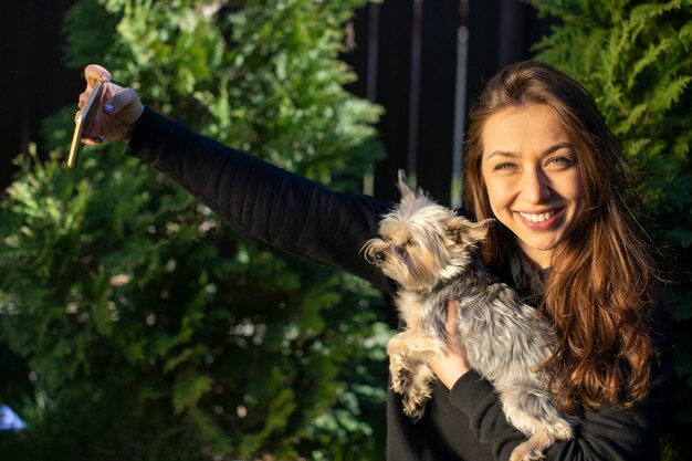 Pretty girl emotionally makes selfies with yorkshire dog