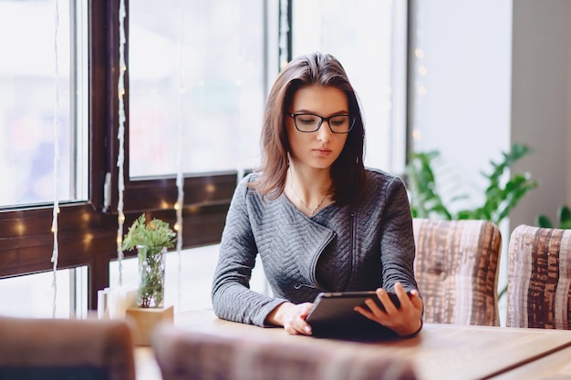 A pretty girl in glasses works on a coffee table