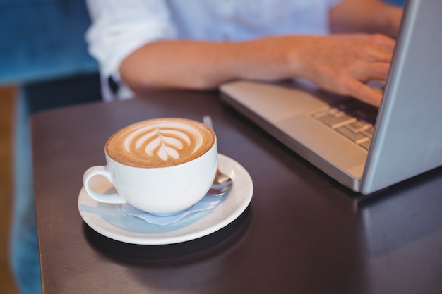  Pretty girl having coffee using laptop