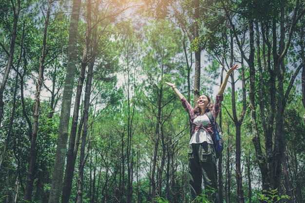 Pretty girl hiker with backpack open arms enjoy the nature in a big forest.