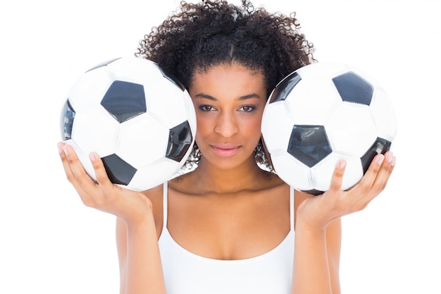 Pretty girl holding footballs and looking at camera