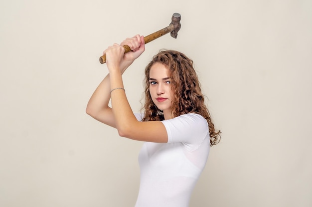 Pretty girl holds a hammer in hands swings to strike