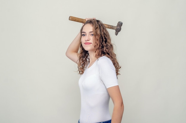 Photo pretty girl holds a hammer in hands swings to strike