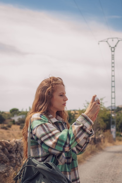 Foto una bella ragazza alza il telefono per scattare una foto dell'ambiente