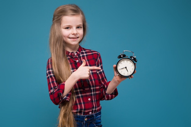 写真 長い髪のシャツでかわいい女の子が時計を保持します。