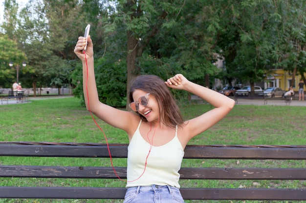 Pretty girl is listening to music in headphones outside. 