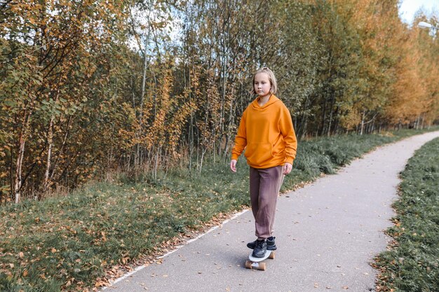 Photo pretty girl learning to skateboard outdoors on beautiful autumn day. children activities and active lifestyle concept.