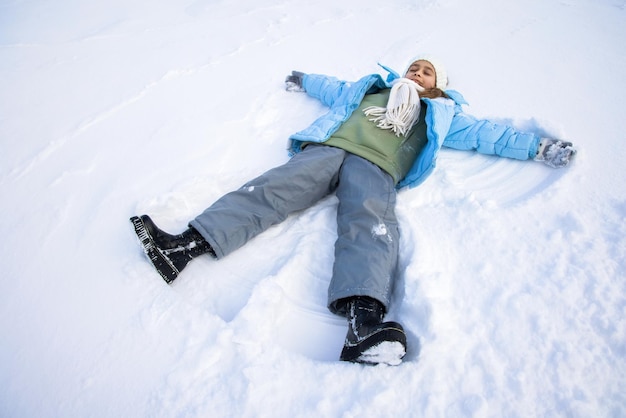 Pretty girl making angel on snow