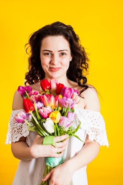 The pretty girl model poses for a camera with tulips