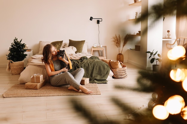 Photo a pretty girl in pajamas rejoices and smiles during the christmas holidays in cozy bedroom interior