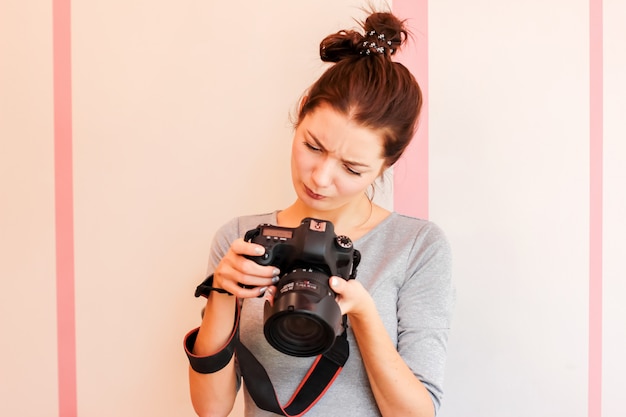 Pretty girl photographer looks into her camera and makes funny d