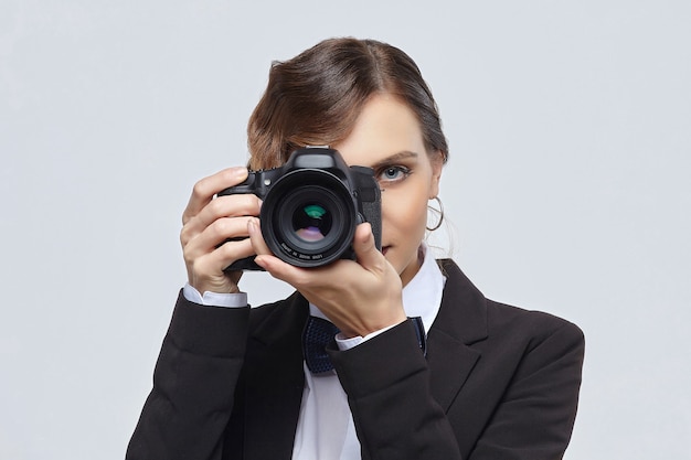 Pretty girl photographer in a men's suit and retro hairstyle on a white background