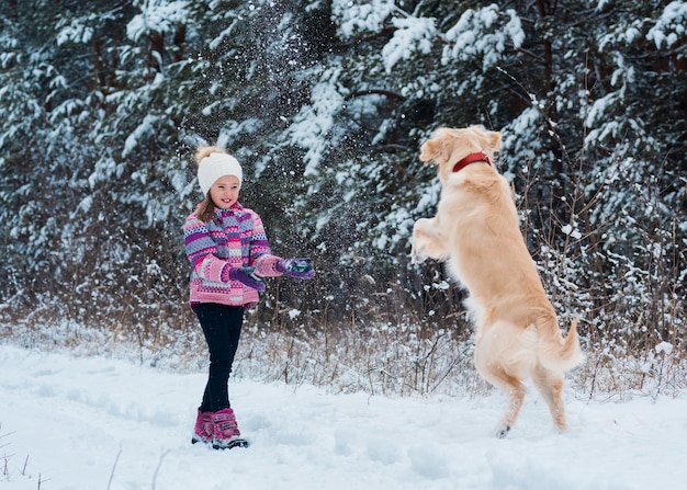 Pretty girl playing with her dog on a winter day