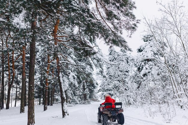 A pretty girl riding a quadrocycle in a picturesque snowy area