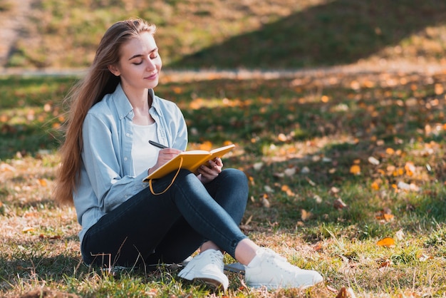 Photo pretty girl sitting in nature and writing