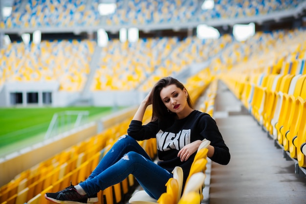 Pretty girl sitting at school stadium. Rest from study.