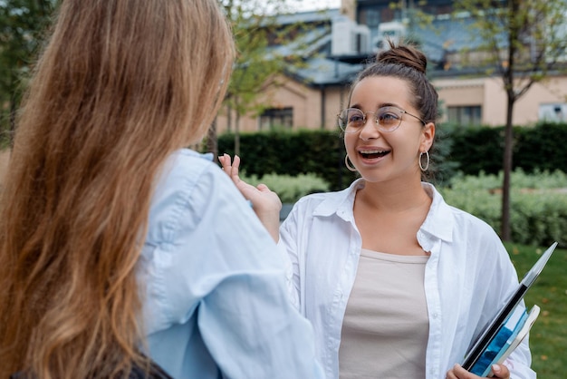 Photo pretty girl student with glasses tells friend student colleague about funny case on a project