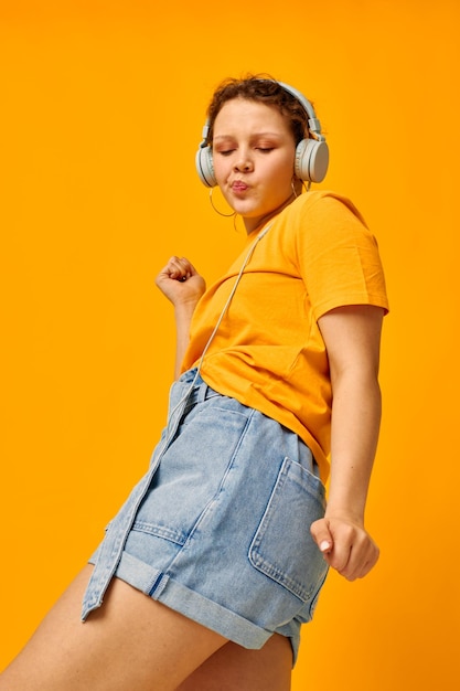 Pretty girl summer style headphones dance yellow background unaltered