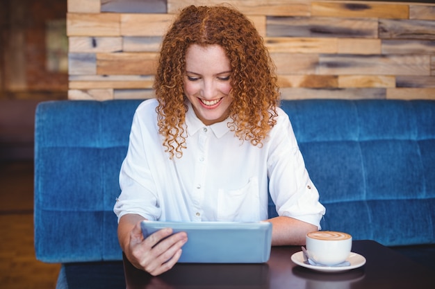 Pretty girl using a small tablet at table