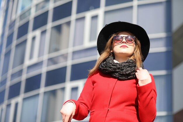 Pretty girl on a walk in red coat in the city