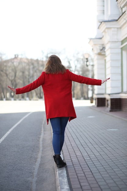 Pretty girl on a walk in a red coat in the city